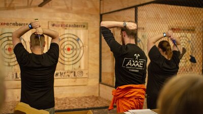 Two people throwing axes at a target