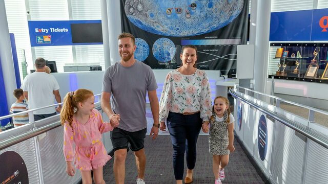 Welcome to Questacon family of 4 walk up the Questacon ramp by the ticket desk
