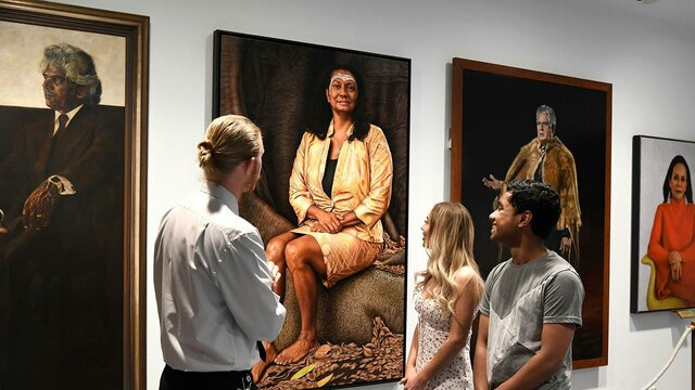 People facing portraits on a wall