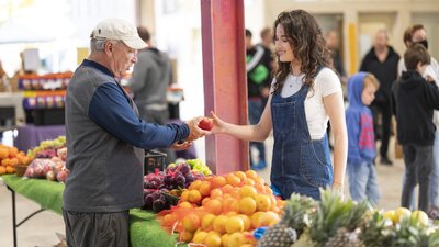 woman buying oranges from stall with grower