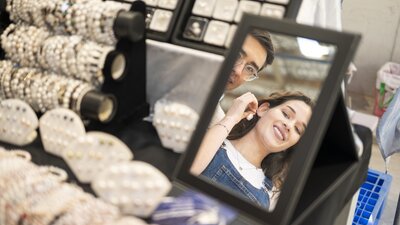 woman holding up jewellry in a mirror