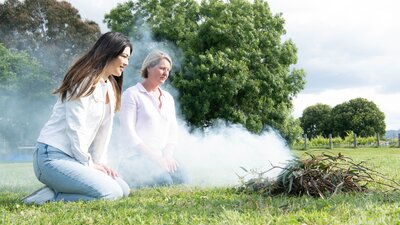 Two women being cleansed during smoking ceremony.