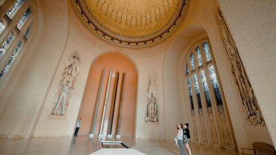 Two woman paying their respects at the tomb of the unknown soldier under an impressive golden dome.