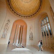 Two woman paying their respects at the tomb of the unknown soldier under an impressive golden dome.