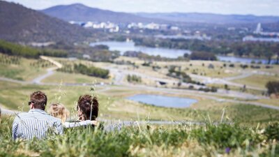 A family looking out over Lake Burley Griffin and the National Arboretum.