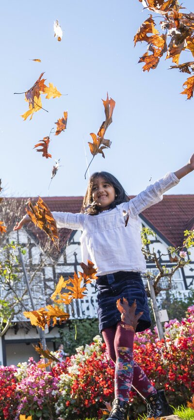 Three kids playing with autumn leaves