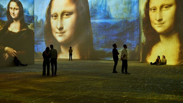 Stepping inside a masterpiece—Mona Lisa surrounds visitors in an immersive art experience. Visitors stand inside an immersive gallery as Mona Lisa projections glow across towering walls.