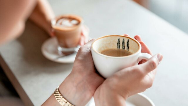 Person holding coffee cup with two hands