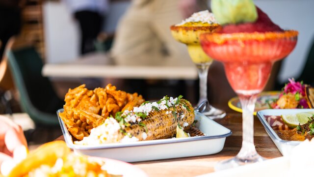 A corn on the cob with bright and colourful frozen margaritas