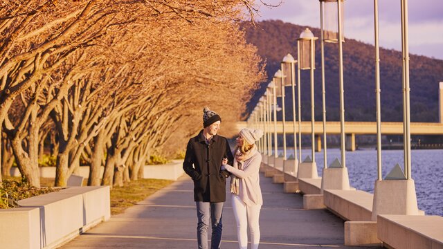 A couple walking by Lake Burley Griffin during winter
