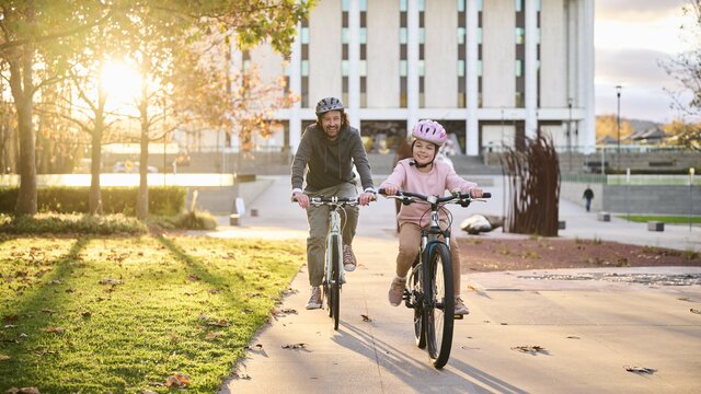 Father and daughter cycling in front of a national attraction