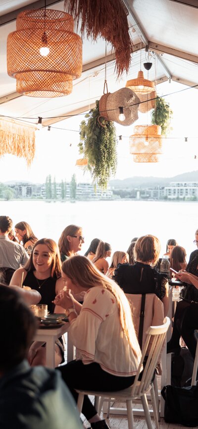 Patrons dining in an outdoor bar by the lake