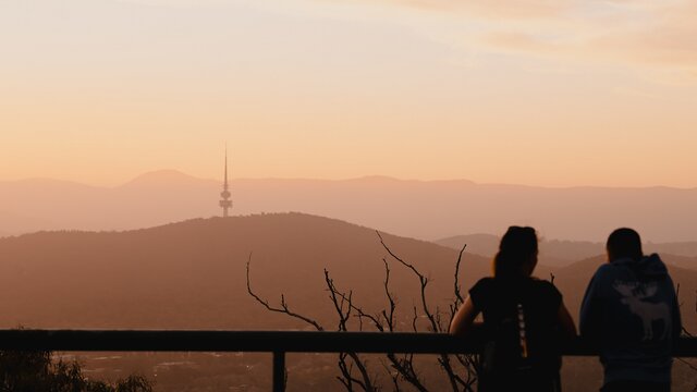 A couple looking out across Canberra as the sun sets.